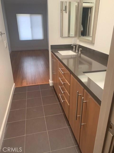 bathroom with tile patterned floors, double vanity, baseboards, and a sink