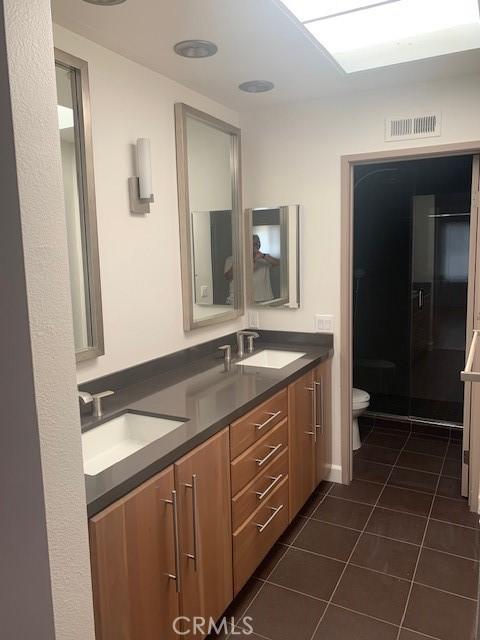 bathroom featuring tile patterned floors, visible vents, toilet, and a sink