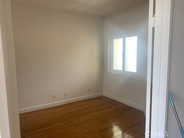 spare room featuring baseboards and wood finished floors