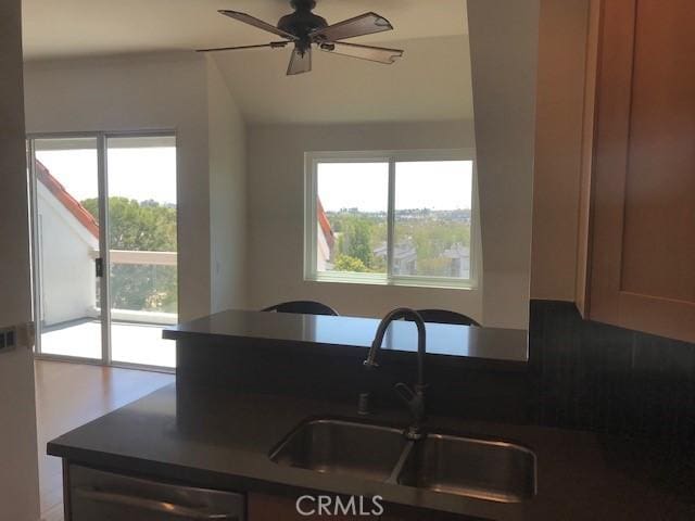 kitchen with dark countertops, ceiling fan, and a sink