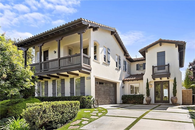 mediterranean / spanish-style home with a balcony, stucco siding, french doors, and a garage