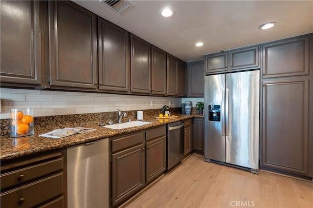 kitchen featuring visible vents, light wood-style flooring, a sink, appliances with stainless steel finishes, and tasteful backsplash