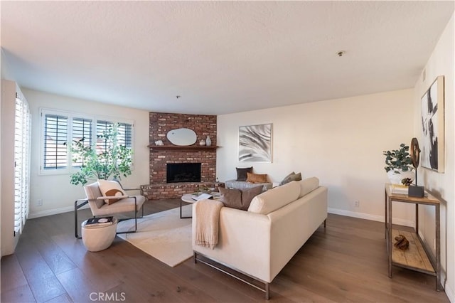 living room featuring baseboards, a brick fireplace, and wood finished floors