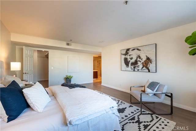 bedroom featuring visible vents, baseboards, and wood finished floors