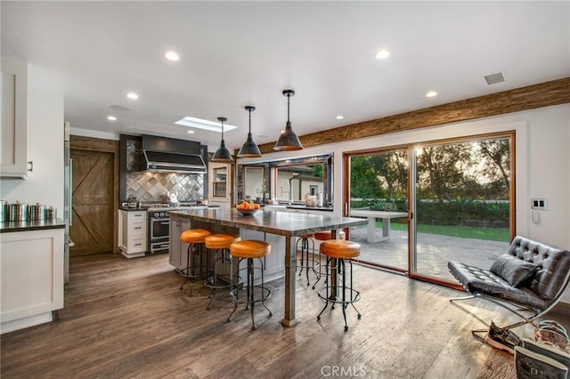 kitchen with dark countertops, a breakfast bar area, custom range hood, and wood finished floors