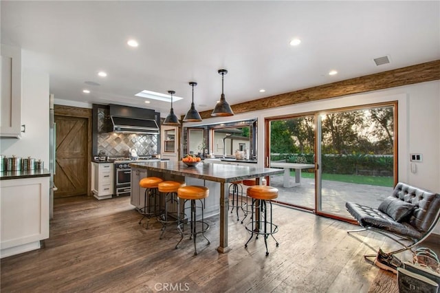 27151 Mission Hills Dr, San Juan Capistrano, CA 92675 - kitchen with dark countertops, premium range hood, a kitchen bar, white cabinetry, and recessed lighting