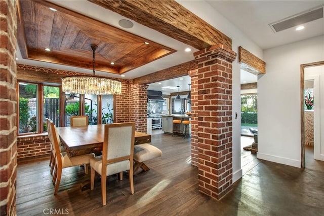 dining space with dark wood-style flooring, a tray ceiling, visible vents, and brick wall