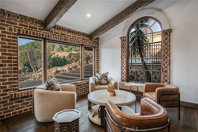 sitting room featuring hardwood / wood-style floors, beam ceiling, and brick wall