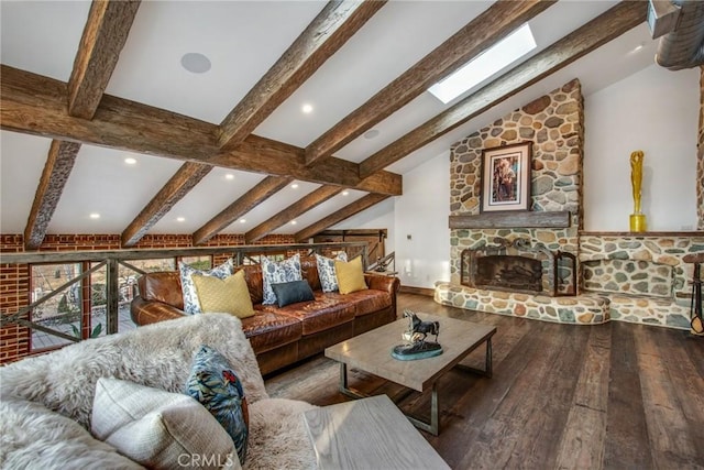 living room with a stone fireplace, vaulted ceiling with skylight, and hardwood / wood-style floors