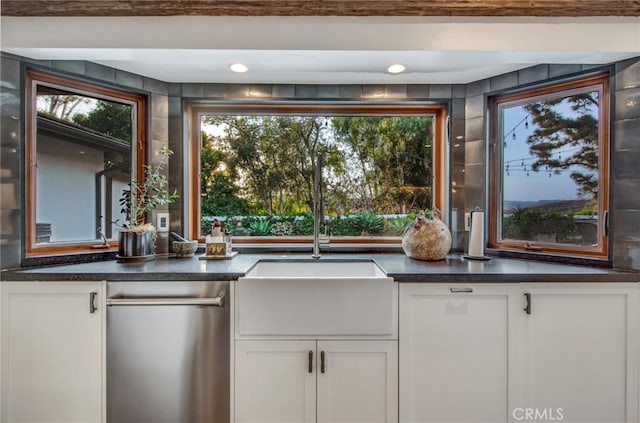 kitchen featuring dark countertops, white cabinets, a healthy amount of sunlight, and a sink