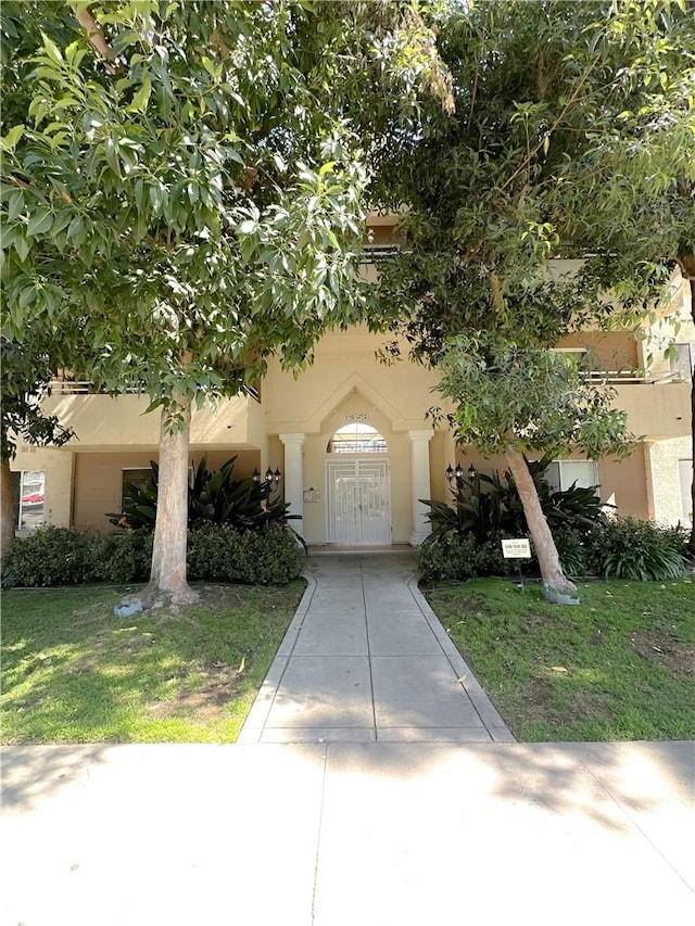 view of front of house with stucco siding and a front lawn