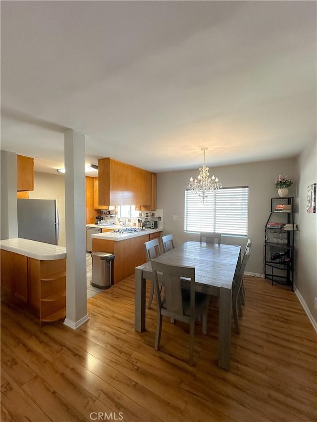 dining area featuring baseboards, a notable chandelier, and wood finished floors