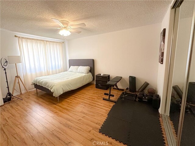 bedroom featuring light wood-style floors, ceiling fan, and a textured ceiling