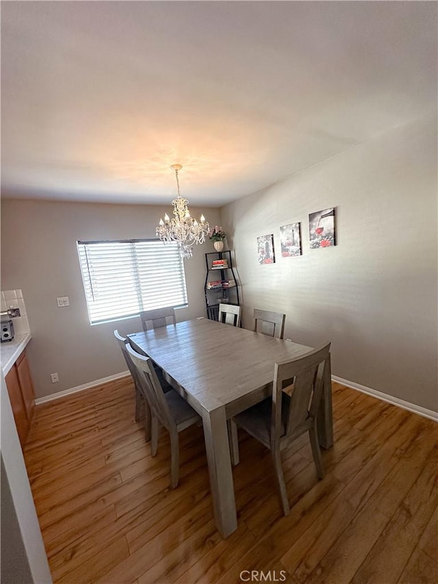 dining room featuring baseboards, a notable chandelier, and light wood finished floors