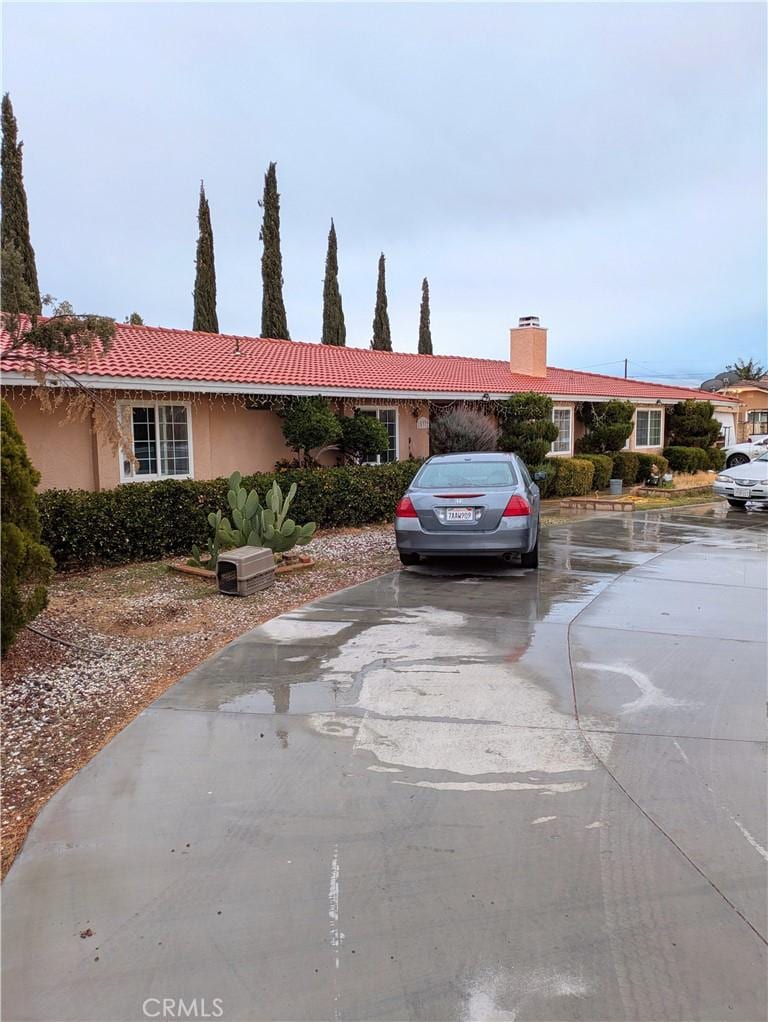 single story home with a tile roof, a chimney, and stucco siding