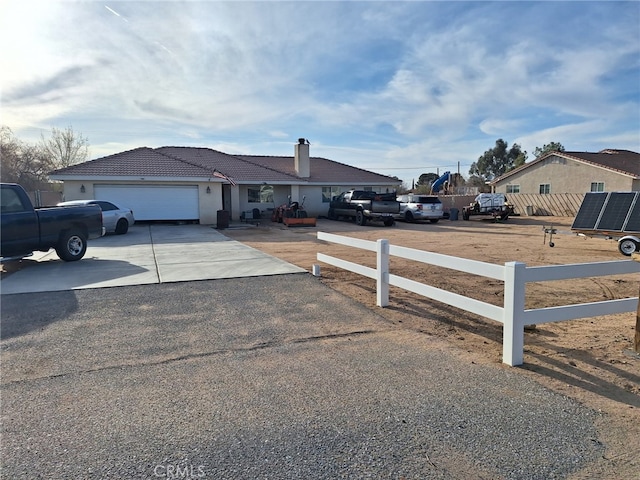 ranch-style home featuring a fenced front yard, a tile roof, concrete driveway, a chimney, and an attached garage