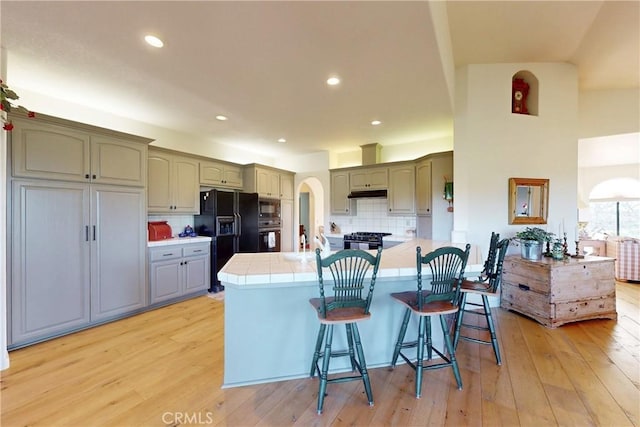2139 Verde Canyon Rd, Arroyo Grande, CA 93420 - kitchen featuring black appliances, arched walkways, a breakfast bar area, light wood-style floors, and recessed lighting