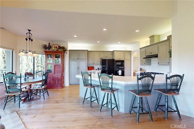 2139 Verde Canyon Rd, Arroyo Grande, CA 93420 - kitchen with black appliances, a peninsula, arched walkways, under cabinet range hood, and decorative backsplash