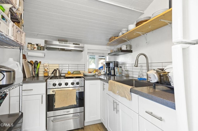 kitchen with open shelves, dark countertops, stainless steel range with gas cooktop, and under cabinet range hood