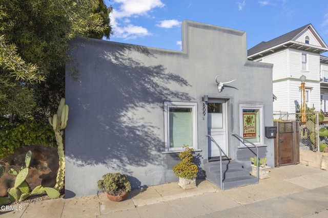 view of front of home featuring stucco siding and fence