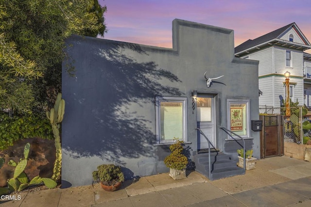 view of front of house featuring stucco siding and fence