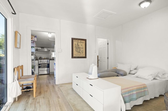 bedroom featuring light wood finished floors and attic access