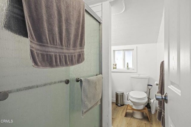 bathroom featuring toilet, wood finished floors, and a shower stall