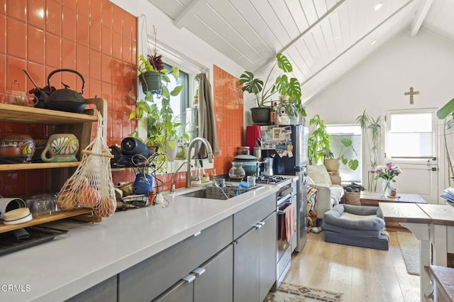 kitchen featuring light wood finished floors, gray cabinets, a sink, light countertops, and vaulted ceiling with beams