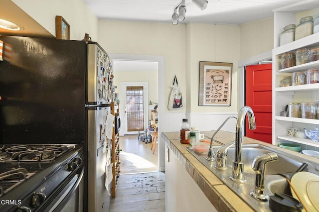 kitchen with black gas range, wood finished floors, and freestanding refrigerator