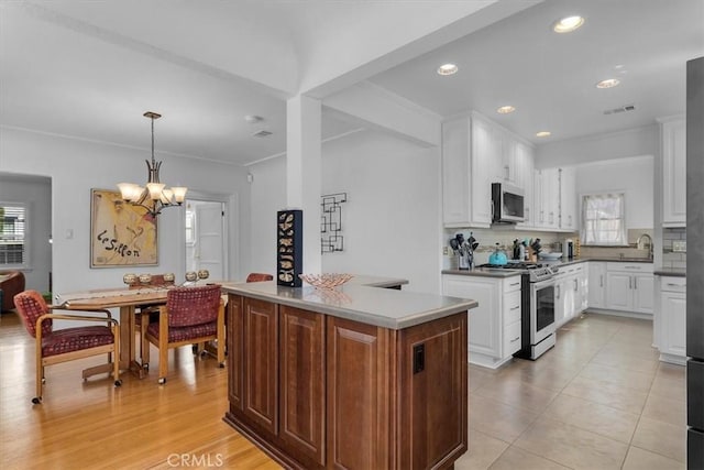 kitchen with visible vents, pendant lighting, white cabinetry, appliances with stainless steel finishes, and decorative backsplash