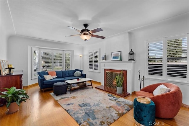 living room with ceiling fan, baseboards, wood finished floors, and a fireplace