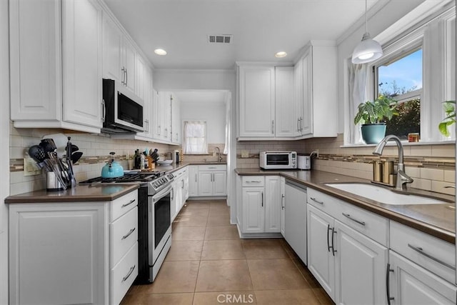 kitchen featuring visible vents, a sink, dark countertops, stainless steel appliances, and light tile patterned floors