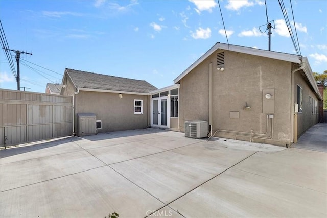 back of house featuring central AC unit, stucco siding, and fence