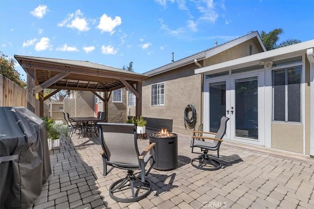 view of patio / terrace with outdoor dining space, an outdoor fire pit, a gazebo, french doors, and a grill