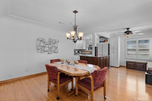 dining space with ceiling fan with notable chandelier, baseboards, visible vents, and light wood-type flooring