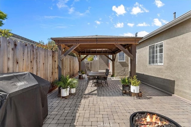 view of patio featuring outdoor dining space, fence, area for grilling, a gazebo, and a fire pit