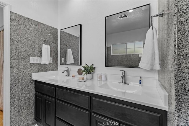 full bath with double vanity, visible vents, and a sink