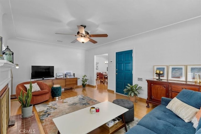 living room with a ceiling fan, a fireplace with flush hearth, wood finished floors, and visible vents