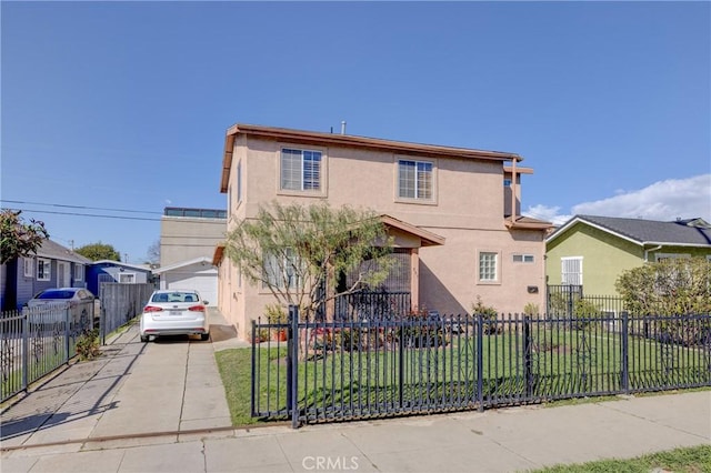 traditional home with a front lawn, driveway, a fenced front yard, and stucco siding