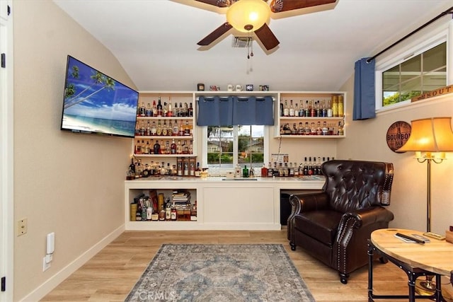 living area with wood finished floors, a dry bar, a ceiling fan, and vaulted ceiling