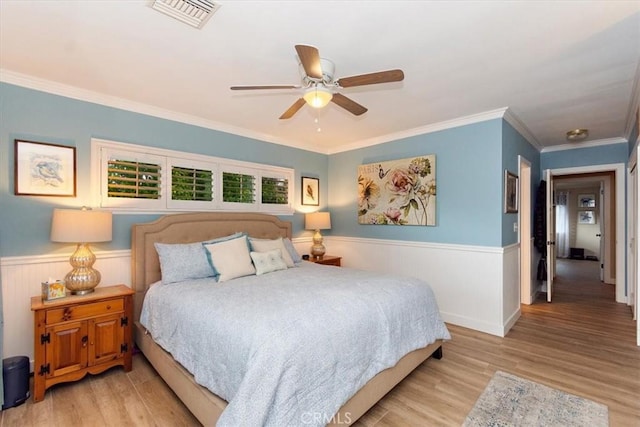 bedroom featuring visible vents, wainscoting, and wood finished floors