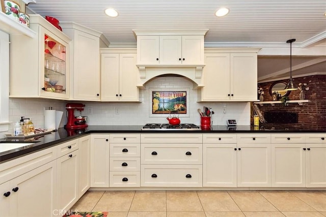 kitchen with light tile patterned floors, decorative backsplash, dark countertops, and glass insert cabinets