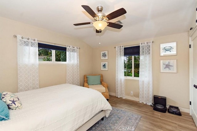 bedroom featuring vaulted ceiling, multiple windows, wood finished floors, and baseboards