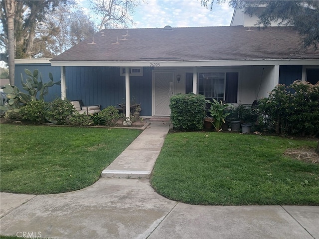 view of front of home featuring roof with shingles, a porch, and a front lawn