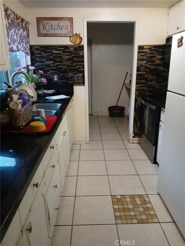 kitchen featuring light tile patterned floors, tasteful backsplash, and freestanding refrigerator