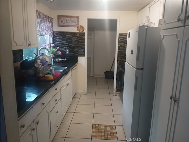 kitchen with dark countertops, decorative backsplash, light tile patterned flooring, white cabinets, and white appliances