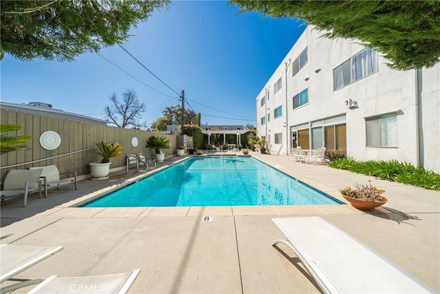 pool with a patio area and fence