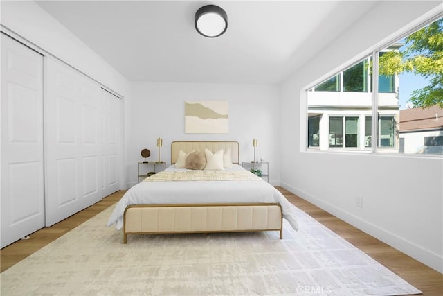 bedroom featuring wood finished floors, baseboards, and a closet