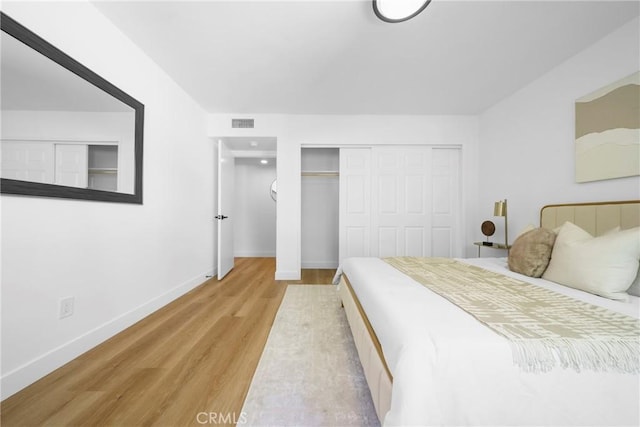 bedroom featuring light wood-style floors, visible vents, a closet, and baseboards