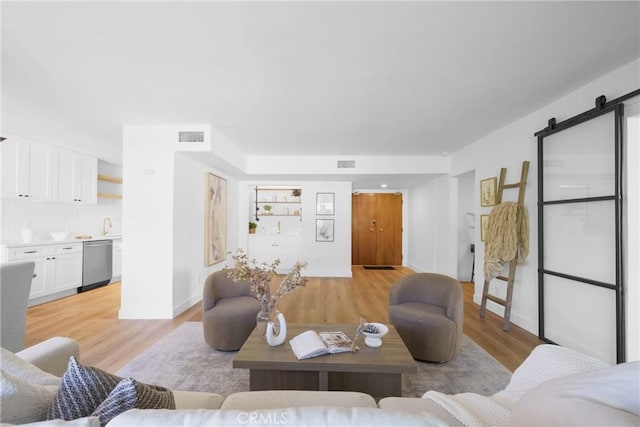 living area featuring a barn door, visible vents, and light wood finished floors